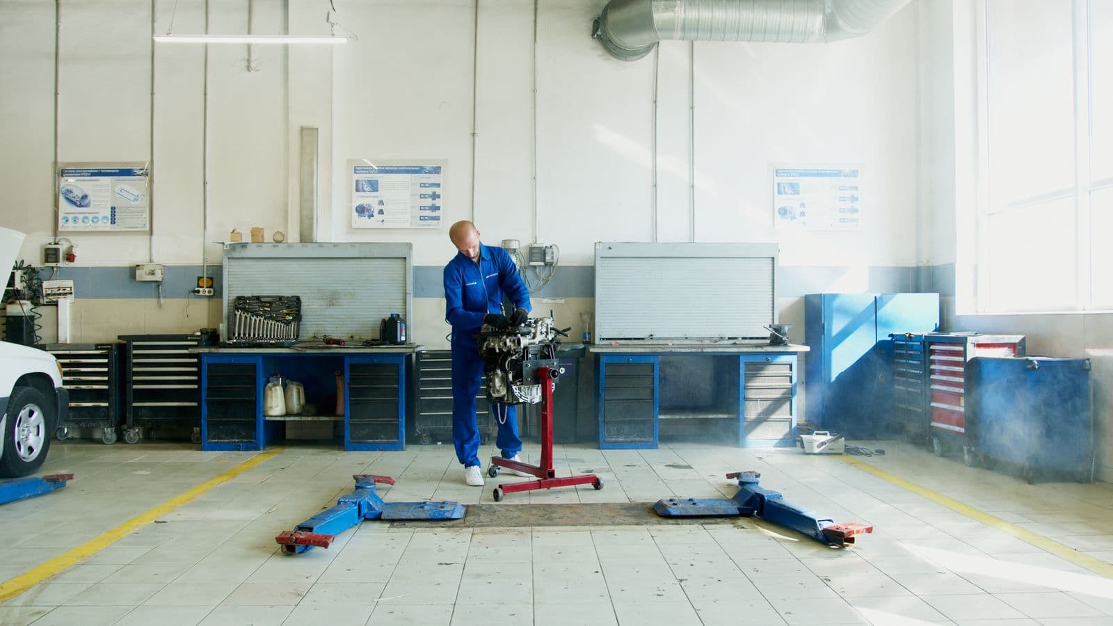 A mechanic working in a bright workshop with tools arranged along the workbenches.