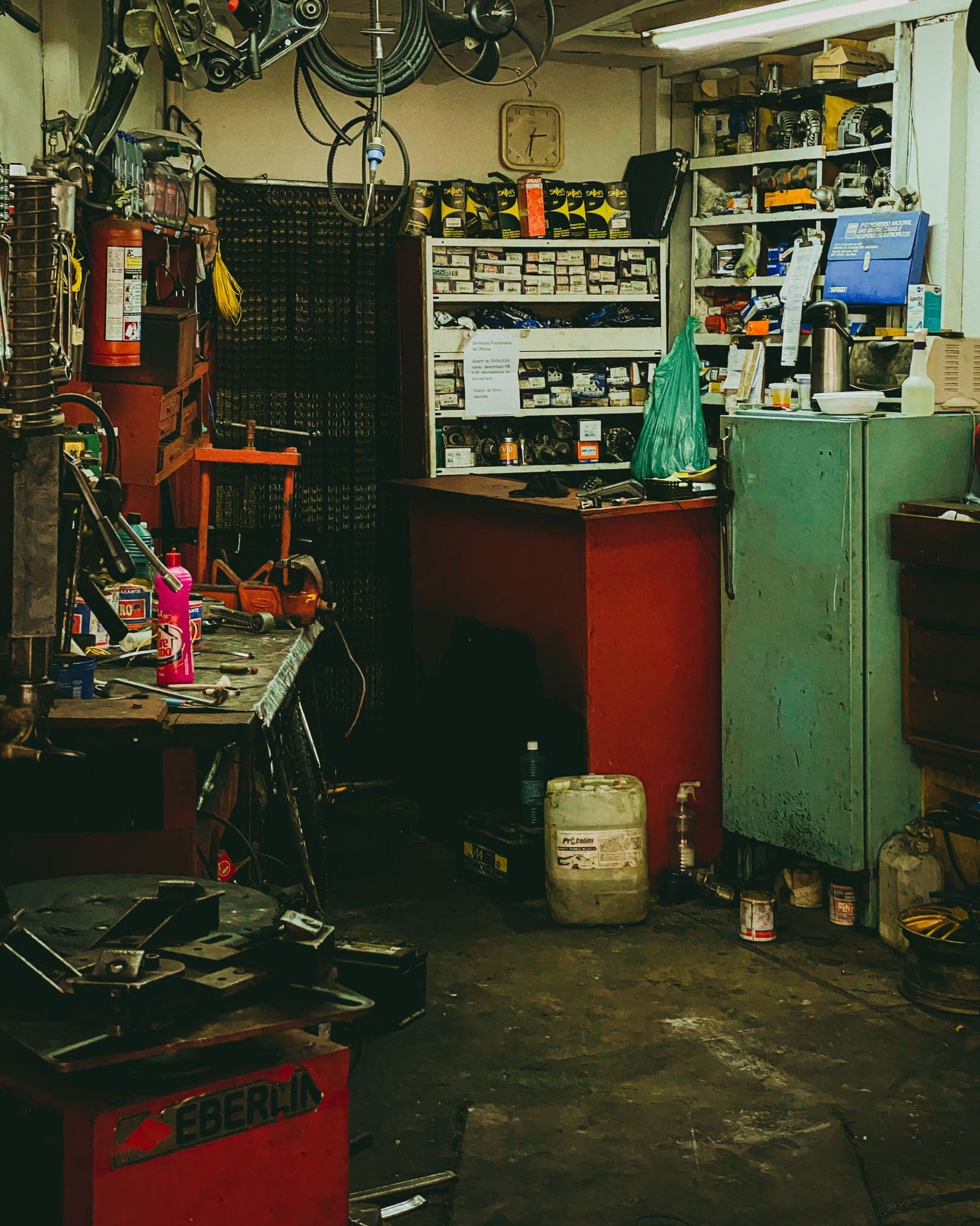 A crowded repair workshop filled with tools, parts, and paperwork.